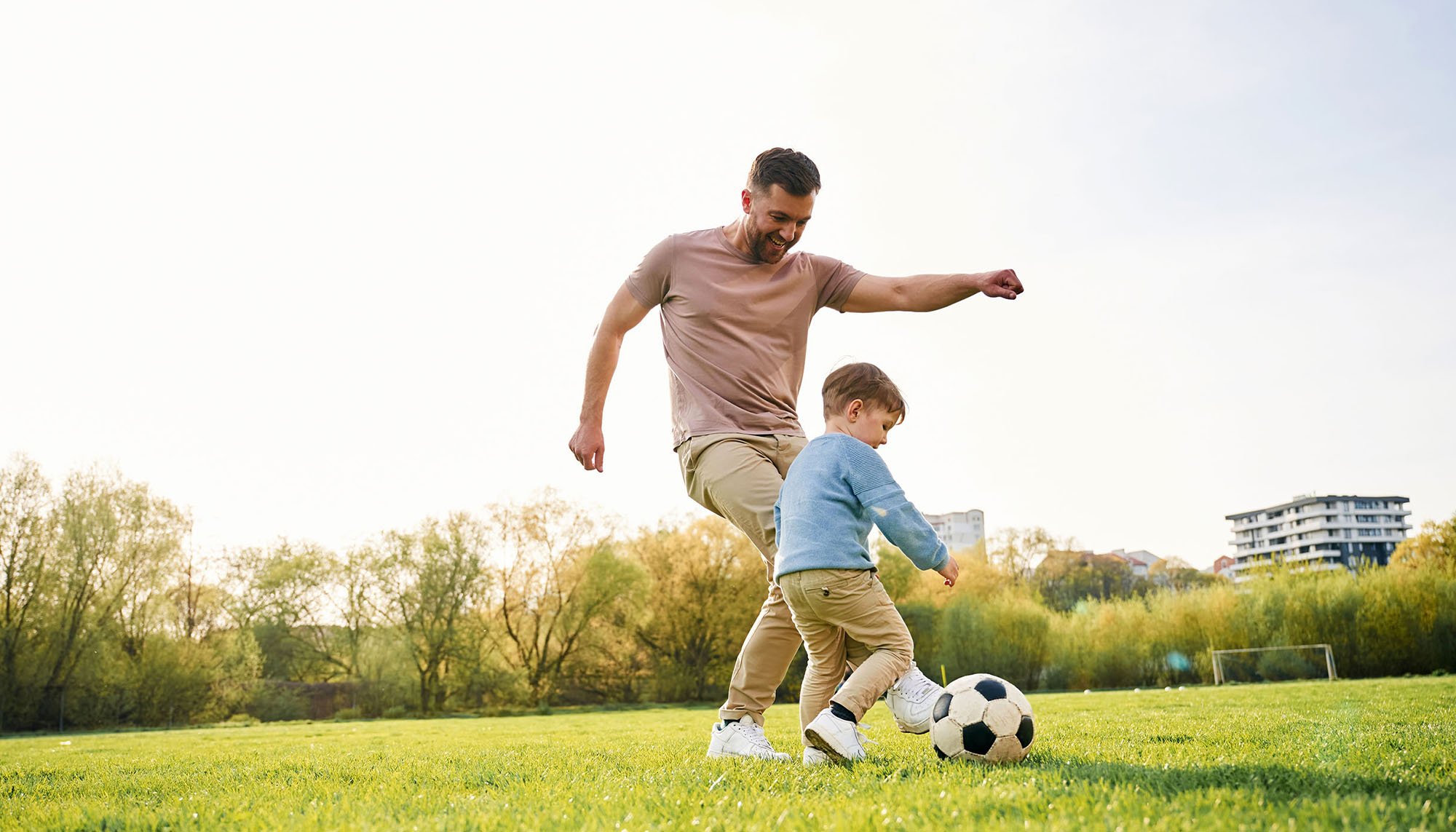 dad playing soccer with son