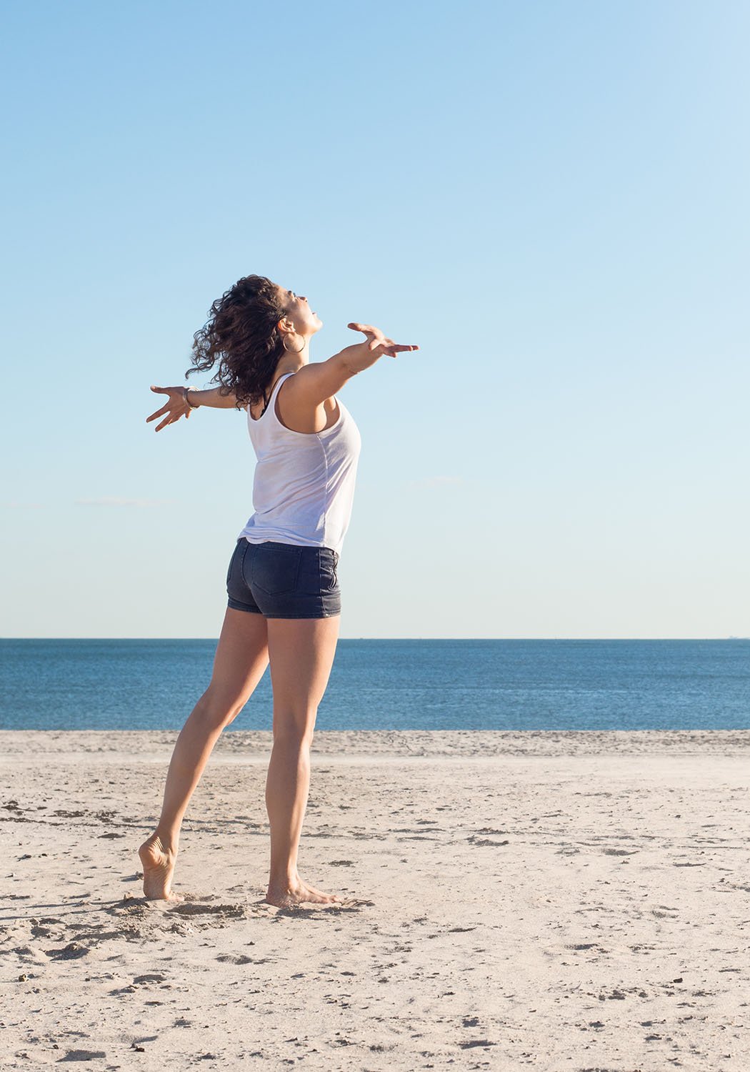woman with arms in the air on the beach